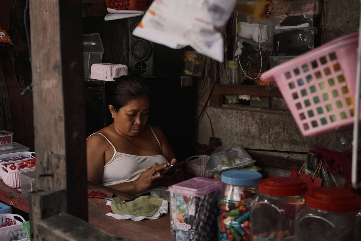 Commerçante qui consulte son téléphone derrière son comptoir dans une petite boutique de quartier