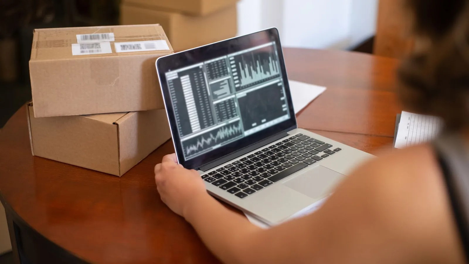 Small business owner reviewing performance charts on a laptop next to shipping boxes
