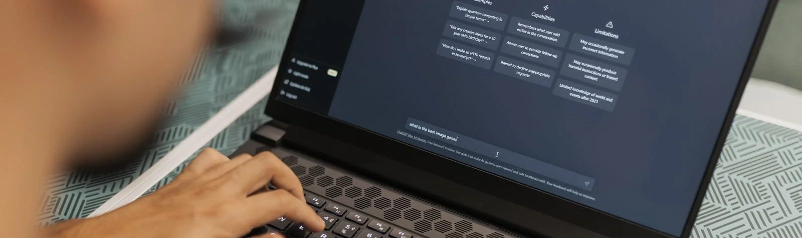 Personne tapant une requête sur un ordinateur portable affichant l'interface de ChatGPT