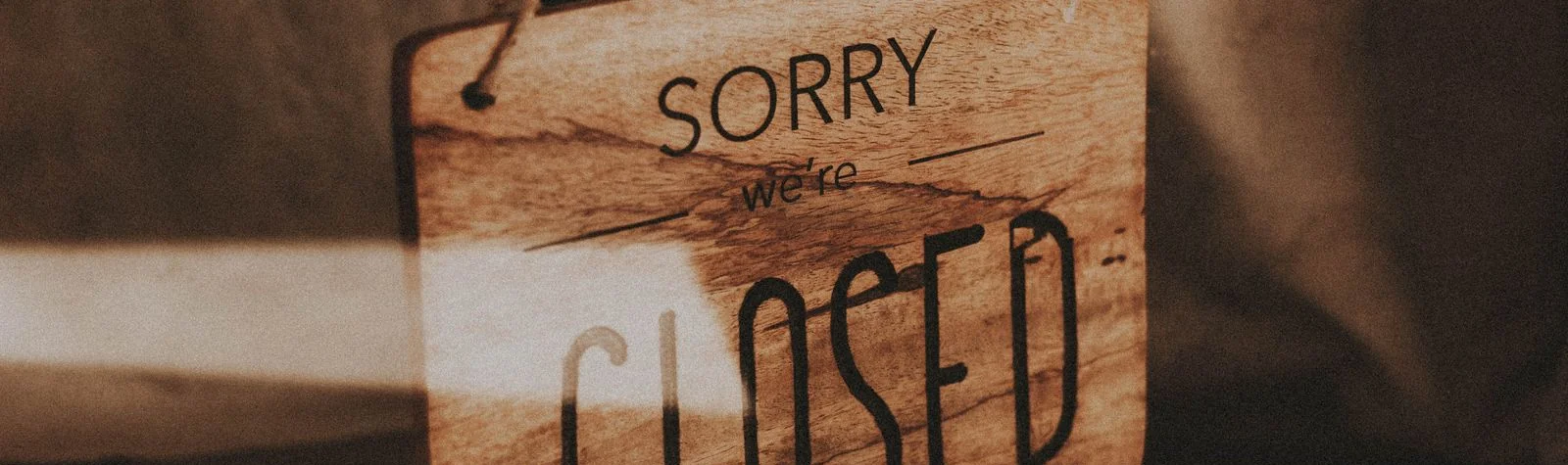 Panneau en bois indiquant Sorry we are closed sur la vitrine d'un commerce fermé