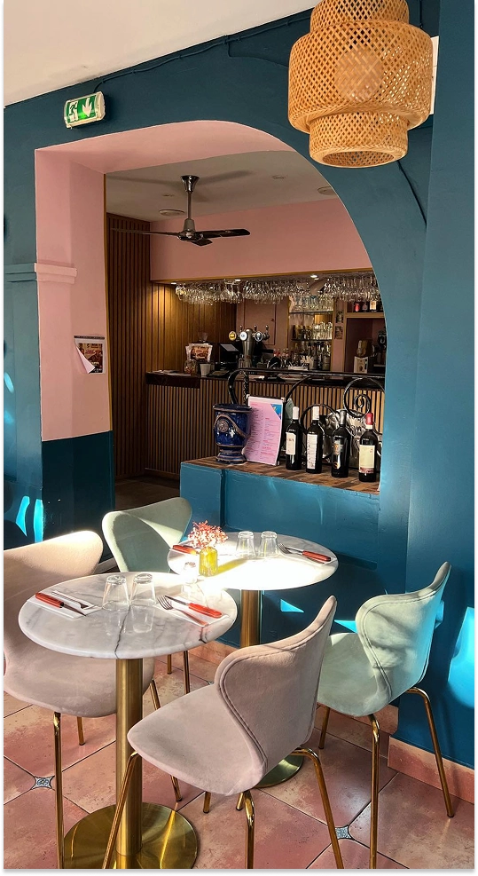 Salle de la pizzeria Italova : tables en marbre, chaises en velours et comptoir aux tons bleu et rose
