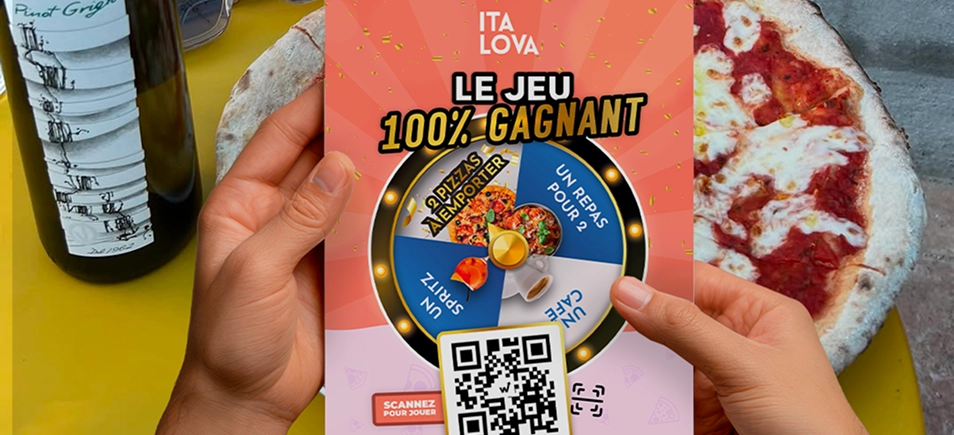 Italova 100% winning game flyer with prize wheel and QR code, held above a table with a pizza