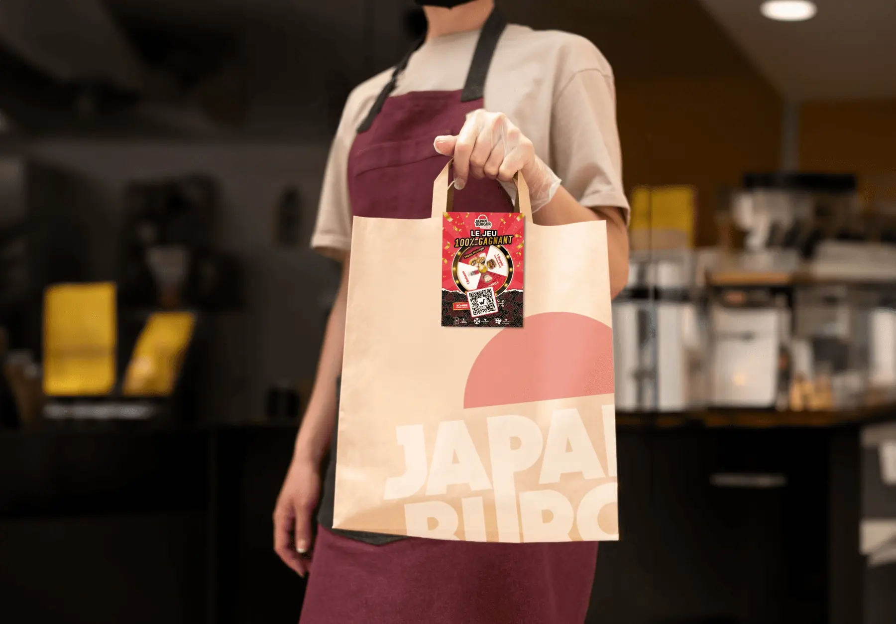 Employée de Japan Burger tendant un sac à emporter orné du flyer du jeu concours