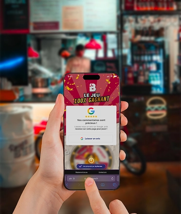 Smartphone in hand showing the Rouge Beef 100% winning game with a Google review being posted